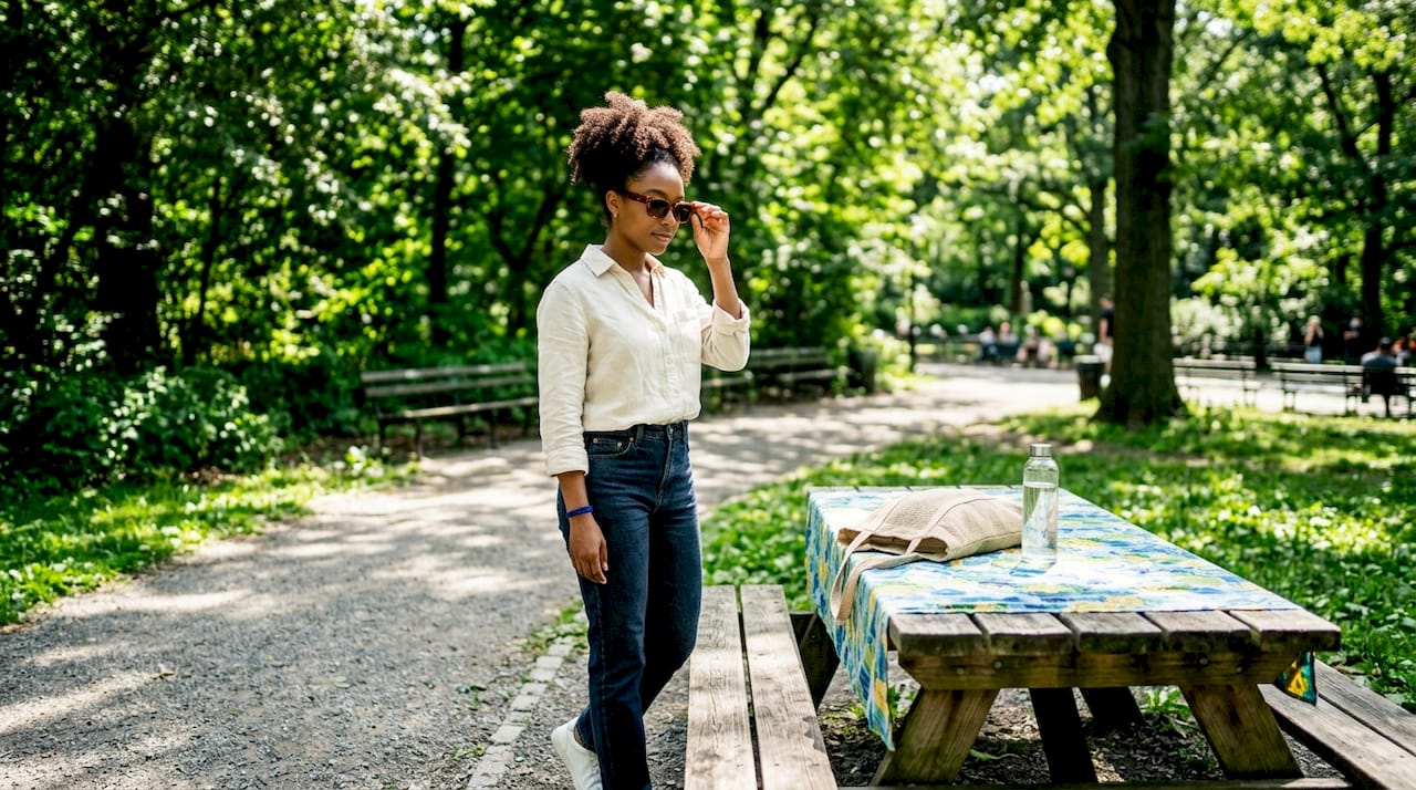 Black woman adjusting black sunglasses outdoors