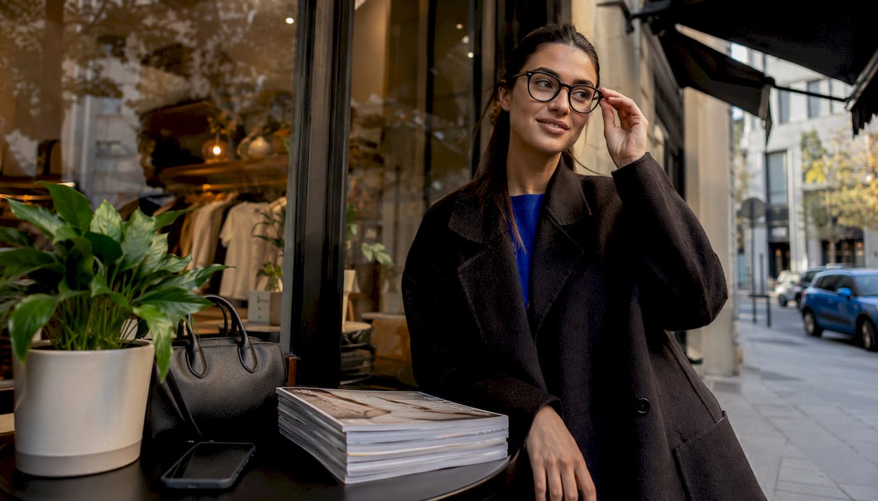 Woman adjusting glasses-style sunglasses outdoors