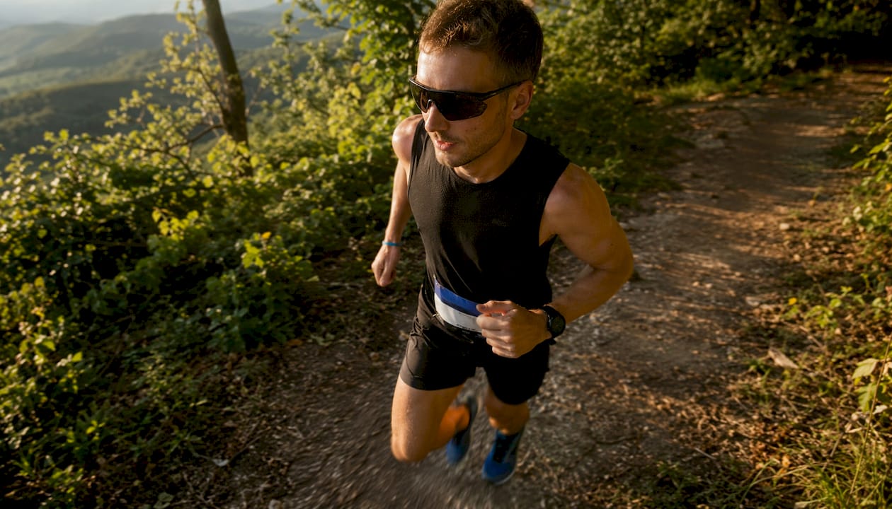 Male runner wearing polarized sunglasses sprinting outdoors