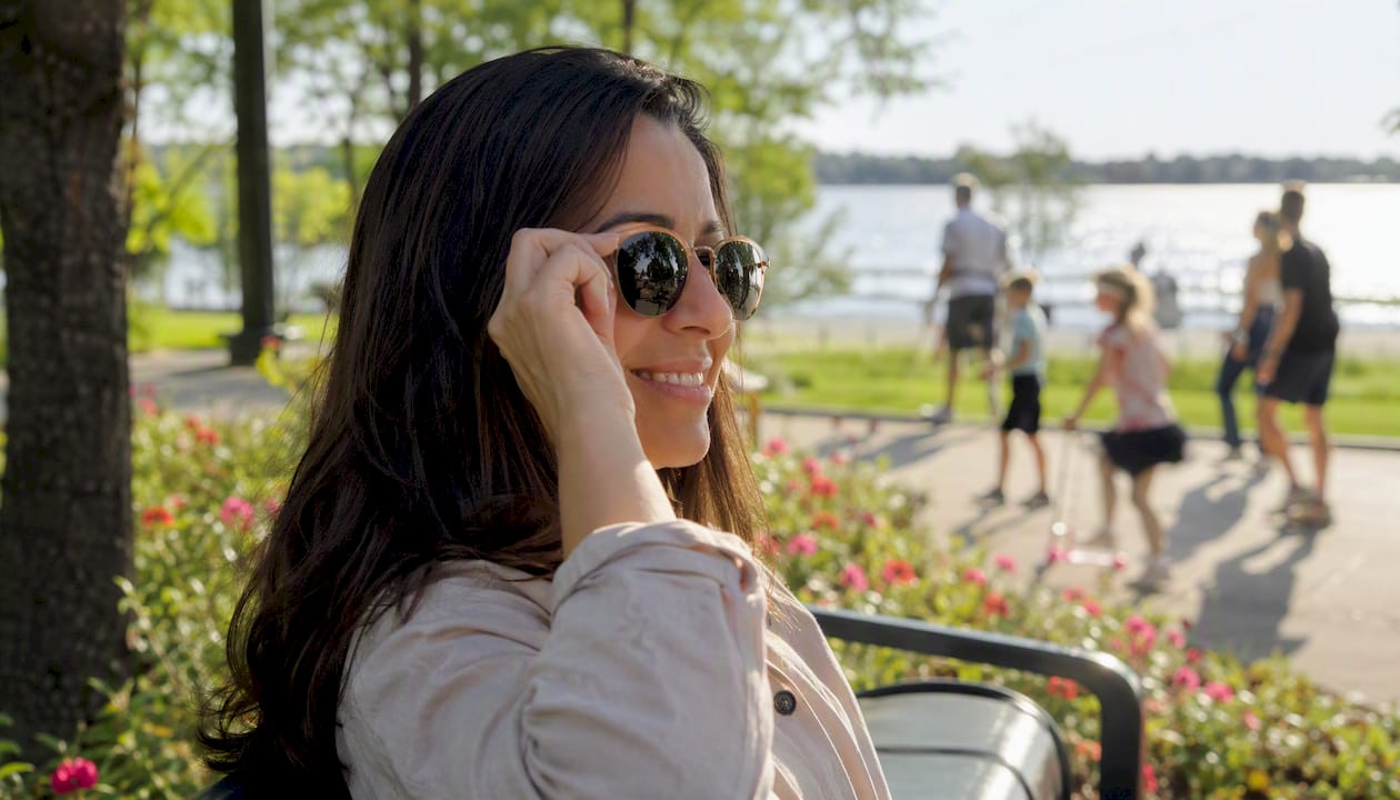 Hand adjusting sunglasses near water glare