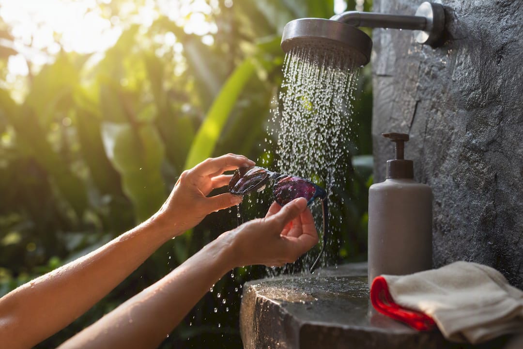 Hands rinsing sunglasses lenses under water