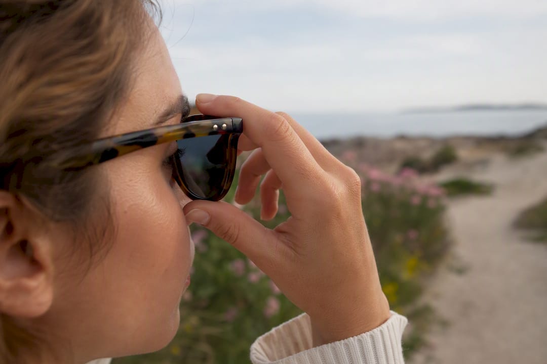 Hand adjusting stylish sunglasses outdoors