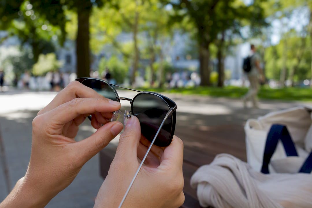 Hands adjusting sunglasses nose pads outdoors